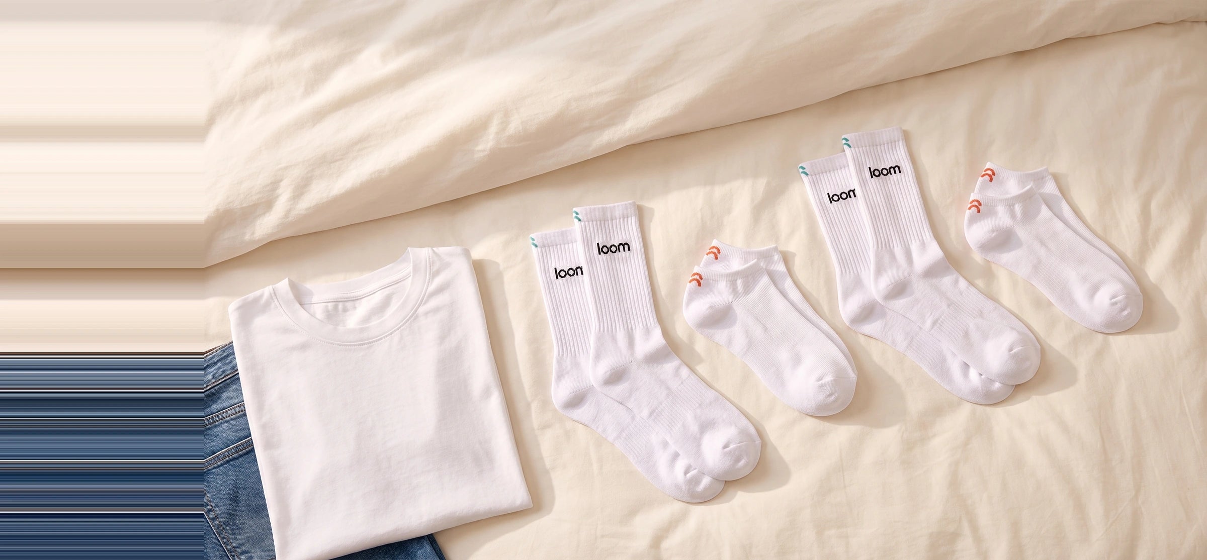 LOOM sokken op bed naast een wit shirt